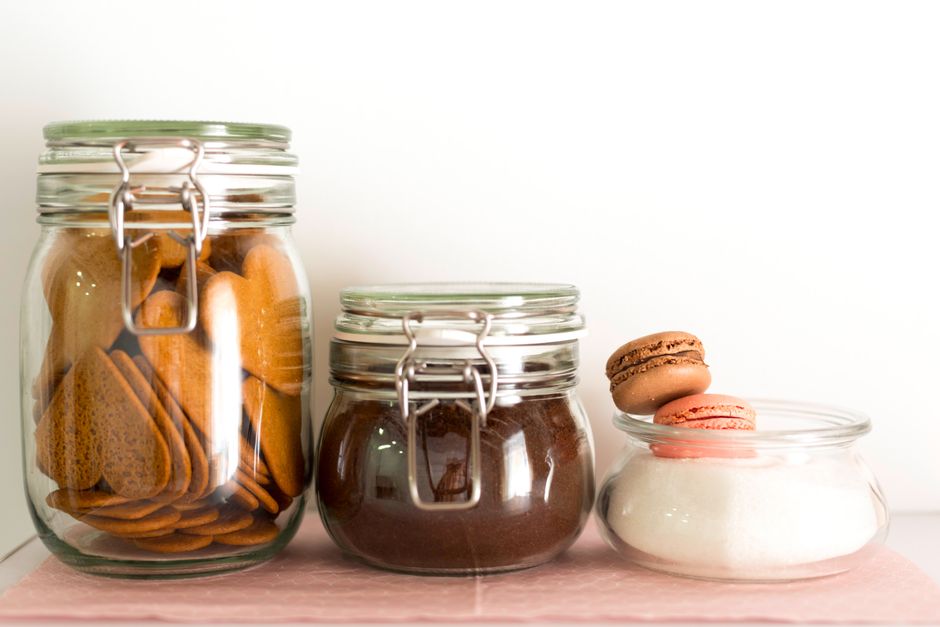 Assorted glass jars filled with cookies and macarons for a sweet kitchen setup.